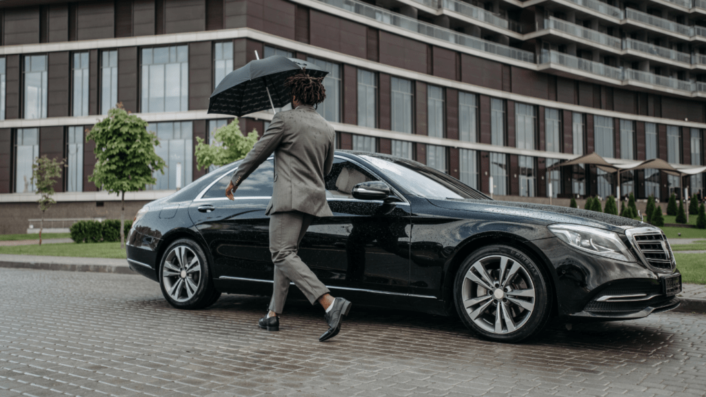 A person in a suit is opening the door of a car.