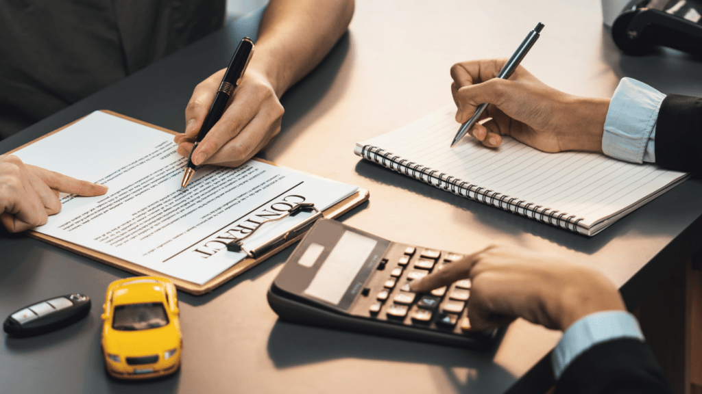 A person is signing a rental agreement with a pen and a toy car