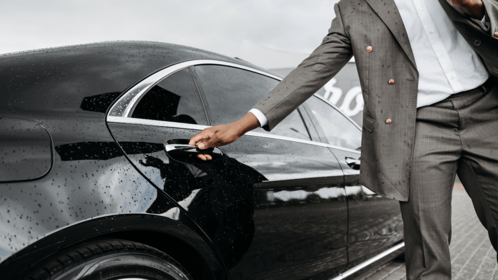 A person in a suit is opening the door of a car.