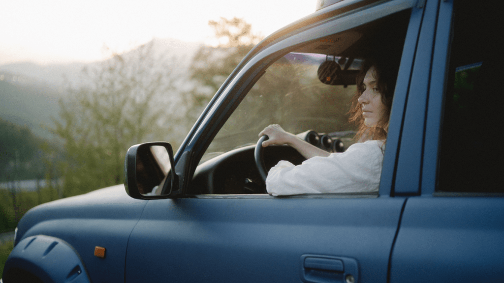 a person driving in a car with mountains in the background