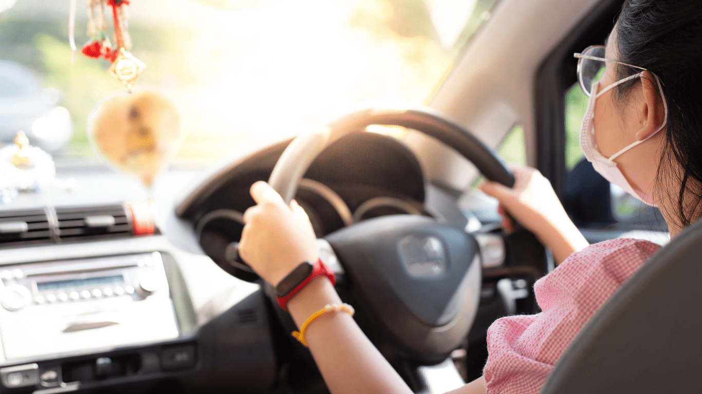 a person wearing a face mask driving a vehicle