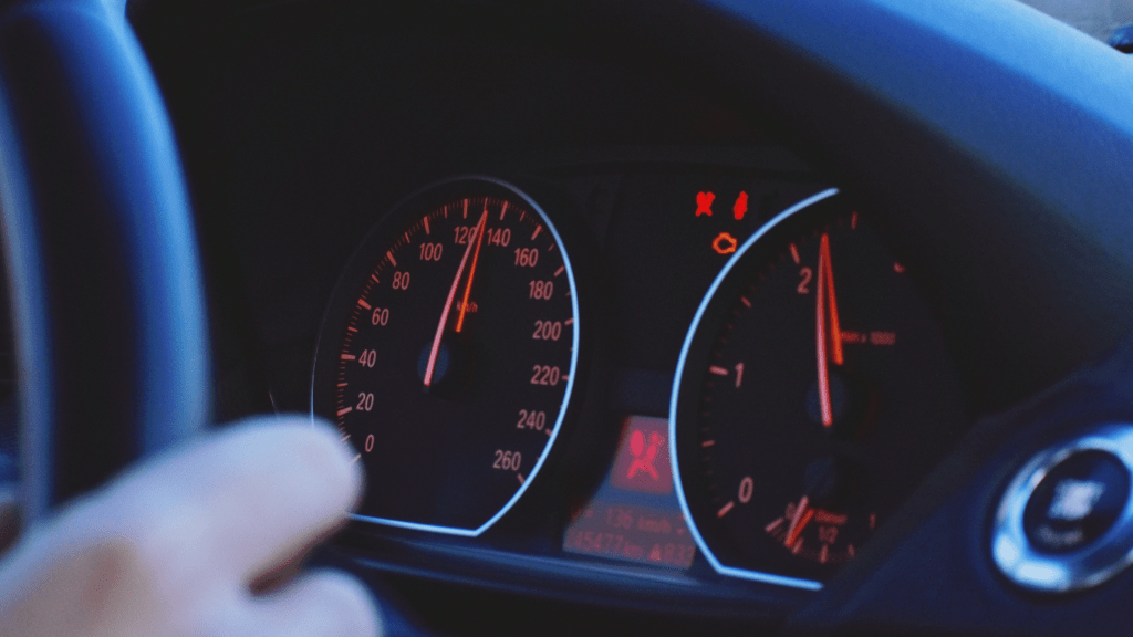 a person driving a car with their hand on the steering wheel