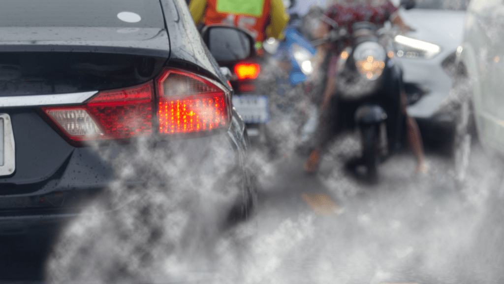 a car driving down the road with smoke coming out of its tailpipe