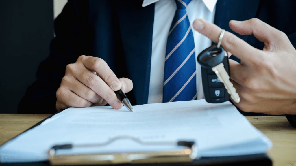 a person in a suit holding a car key and writing on a piece of paper