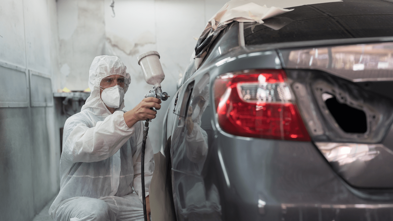 a person in a hazmat suit painting a car