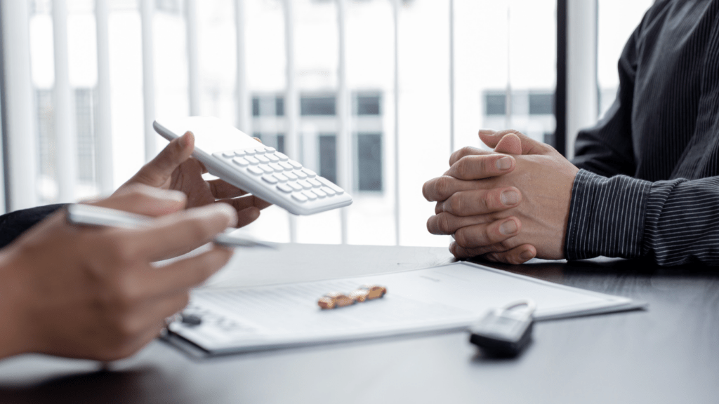 Two people sitting at a desk with a car on the table.