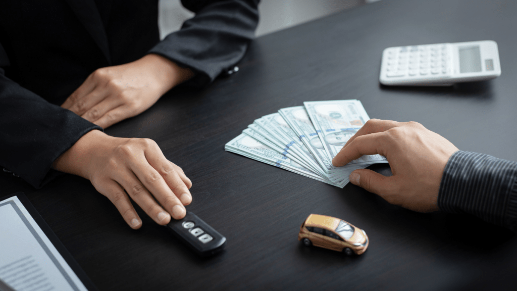 two people sitting at a table with money and a car