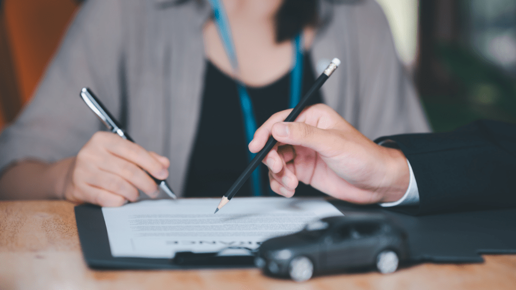 a person signing a contract with a pen and a car