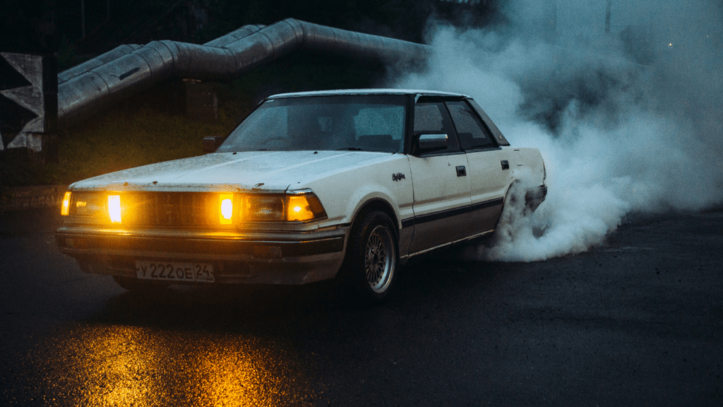 a car driving down the road with smoke coming out of its tailpipe