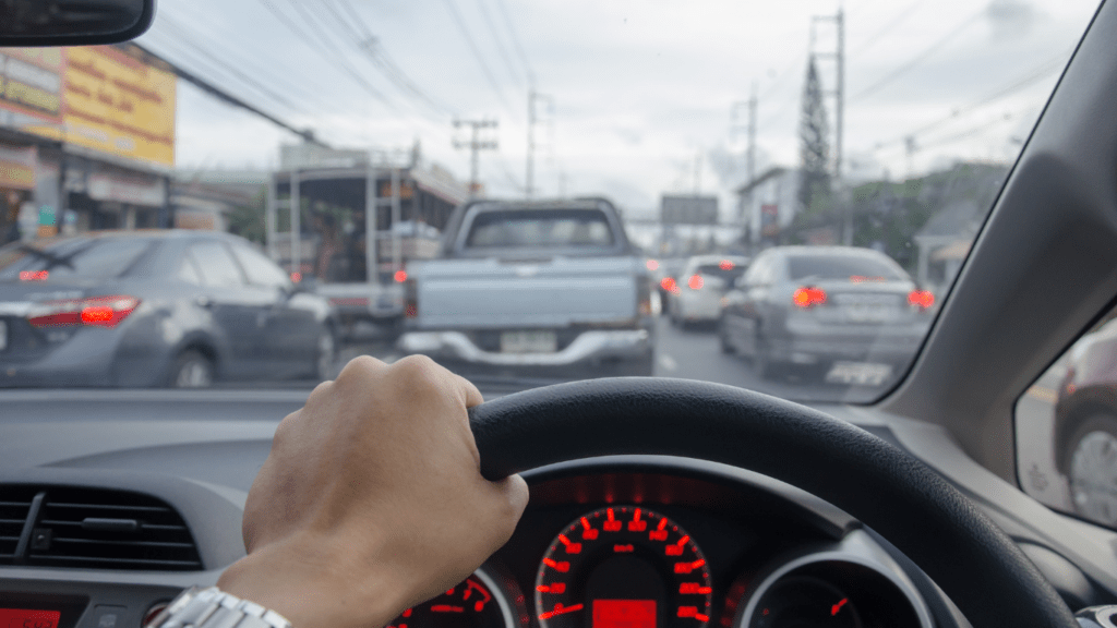 a person driving a car with their hand on the steering wheel