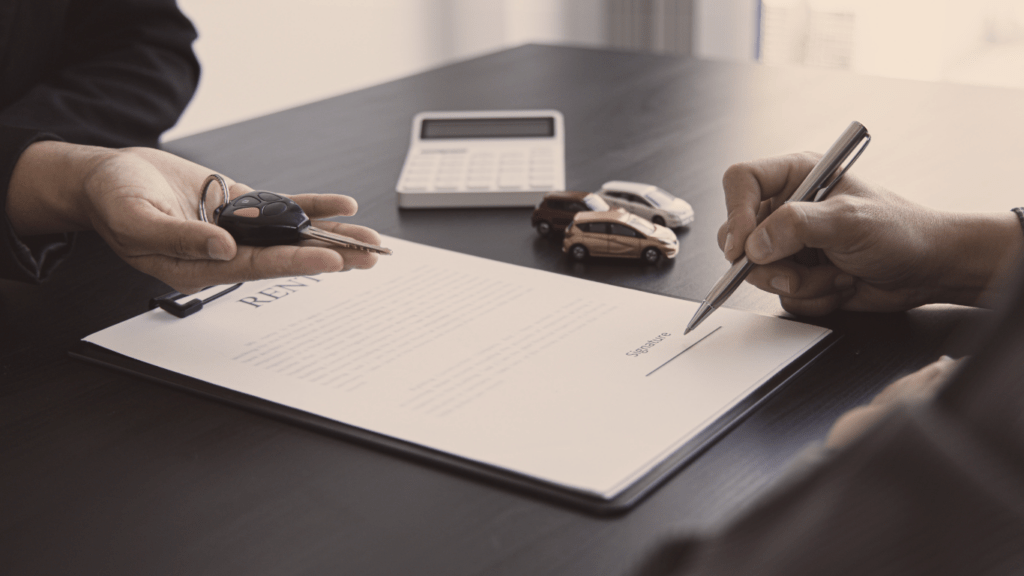 a person handing over a car key to another person at a desk