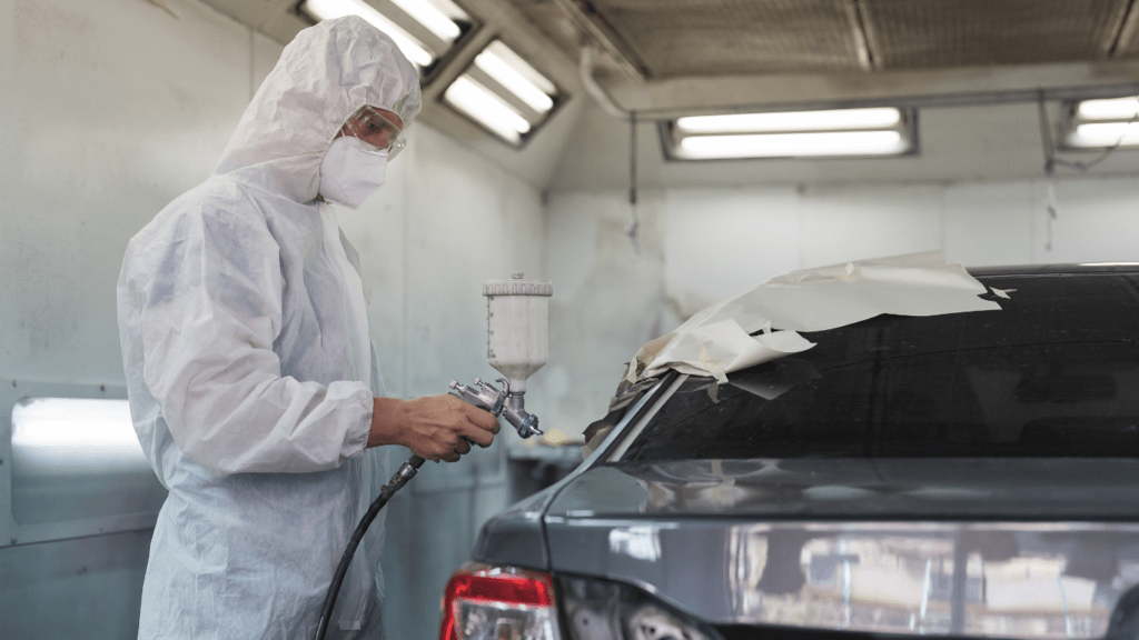 a person in a hazmat suit painting a car