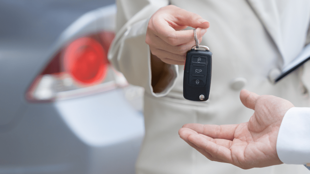 a person in a suit holding a car key and writing on a piece of paper