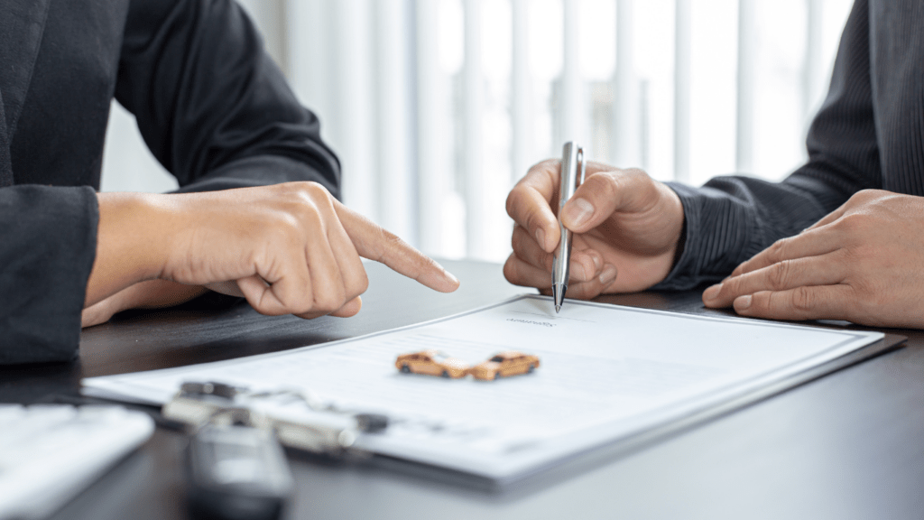 a person signing a contract with a pen and a car