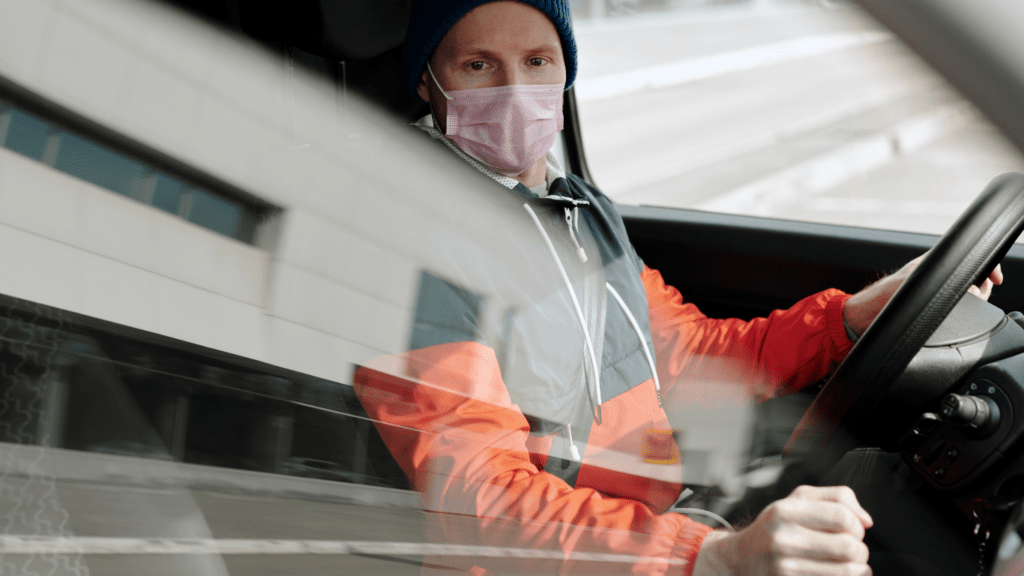 a person wearing a face mask driving a vehicle