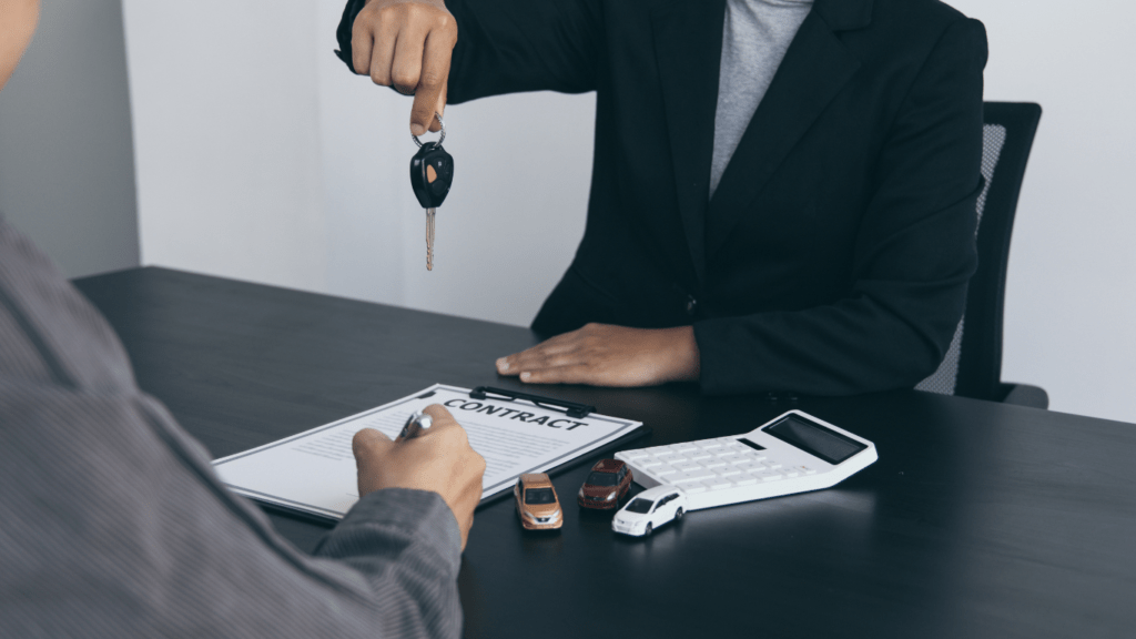 a person handing over a car key to another person at a desk